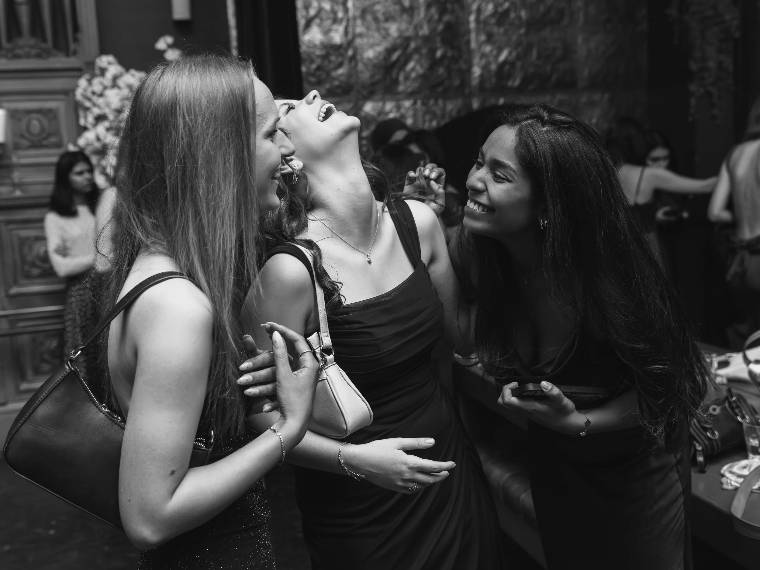 Three women laughing together at a social gathering.