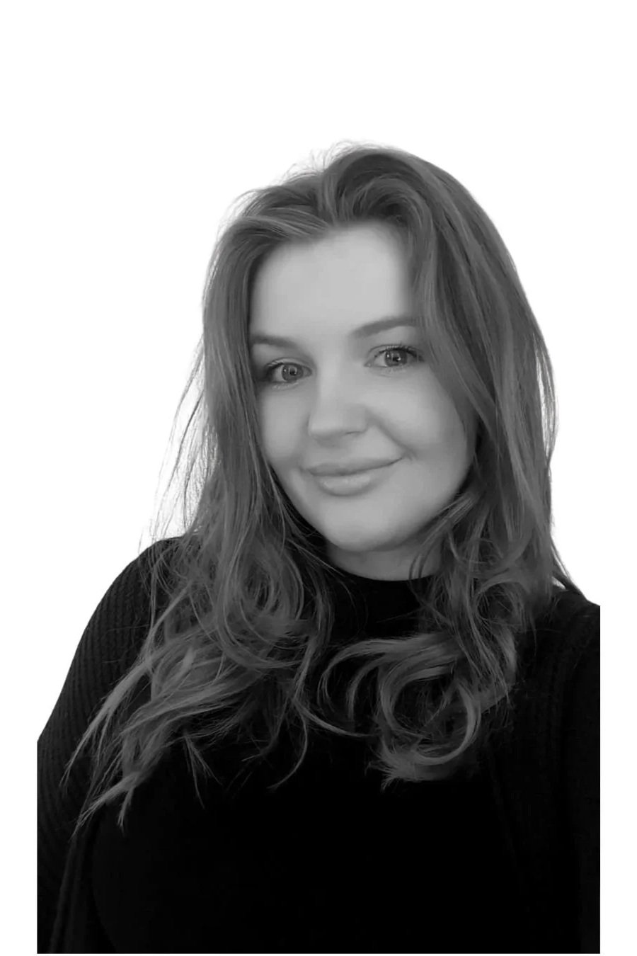 Black and white portrait of a smiling person with long hair wearing a dark top.