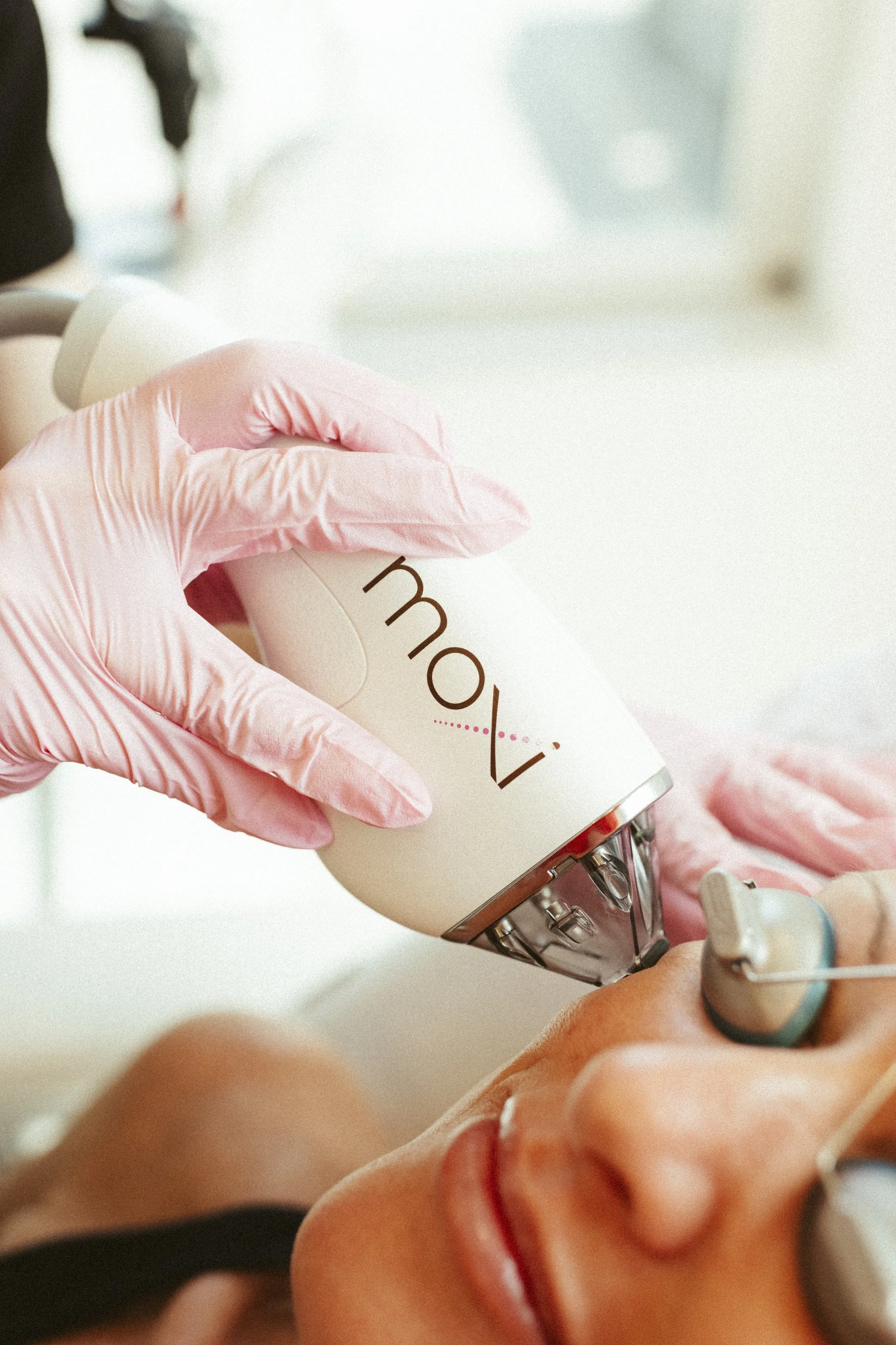 A healthcare professional wearing pink gloves is administering a shot to a person's arm using a syringe.