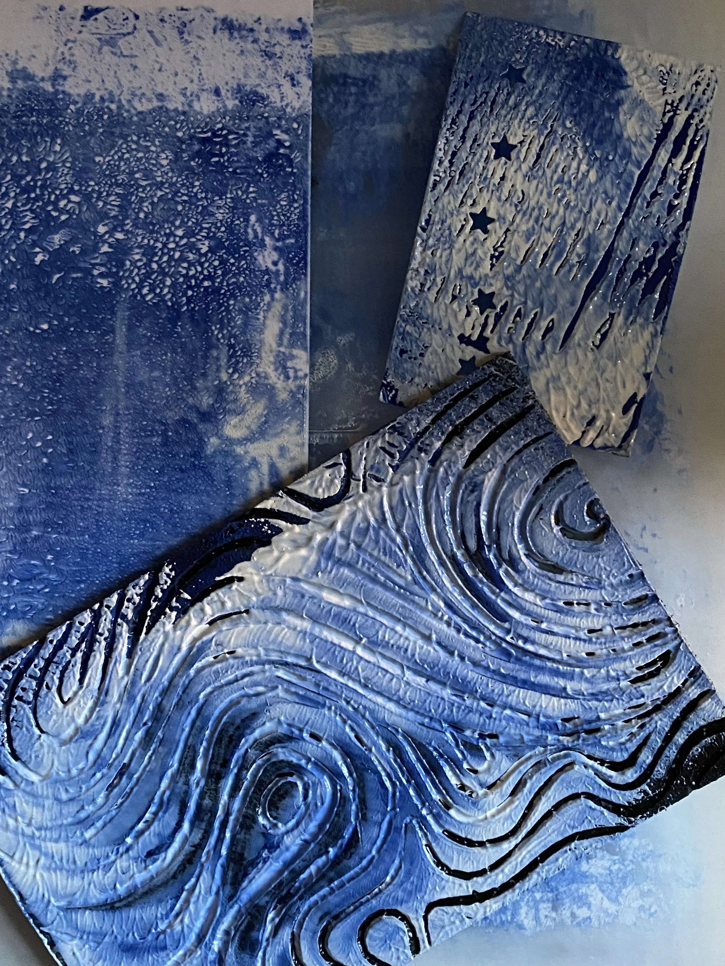 Silver metallic canvases with embossed, swirling patterns and star cutouts, arranged in a layered display.