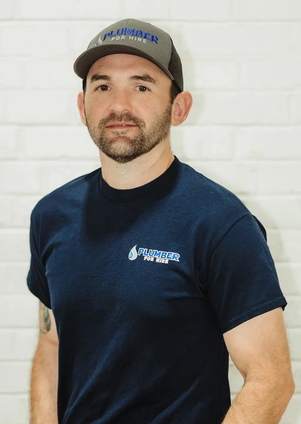 Man wearing a "Plumber for Hire" cap and t-shirt