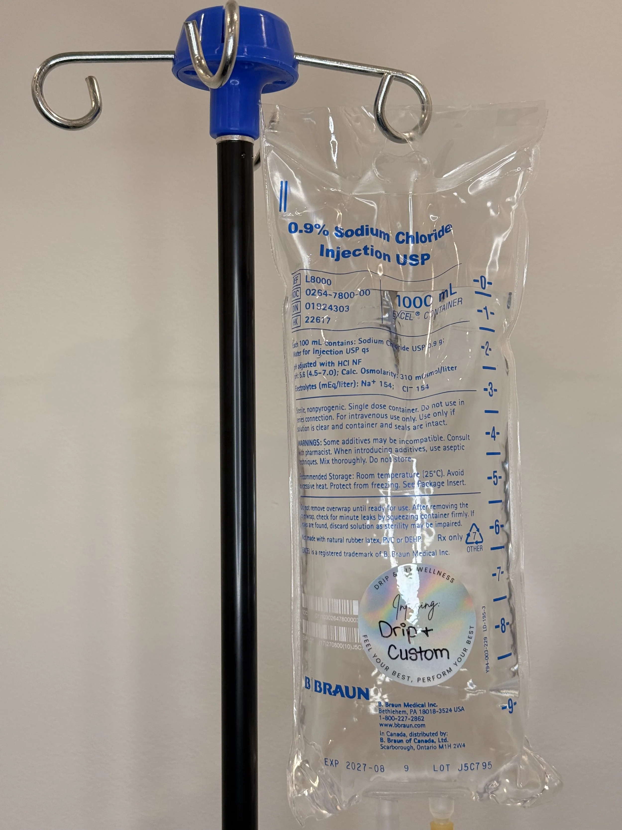 A clear medical IV bag labeled '0.9% Sodium Chloride Injection USP' with a blue top, hanging from a metal stand, with a black tube extending downward.