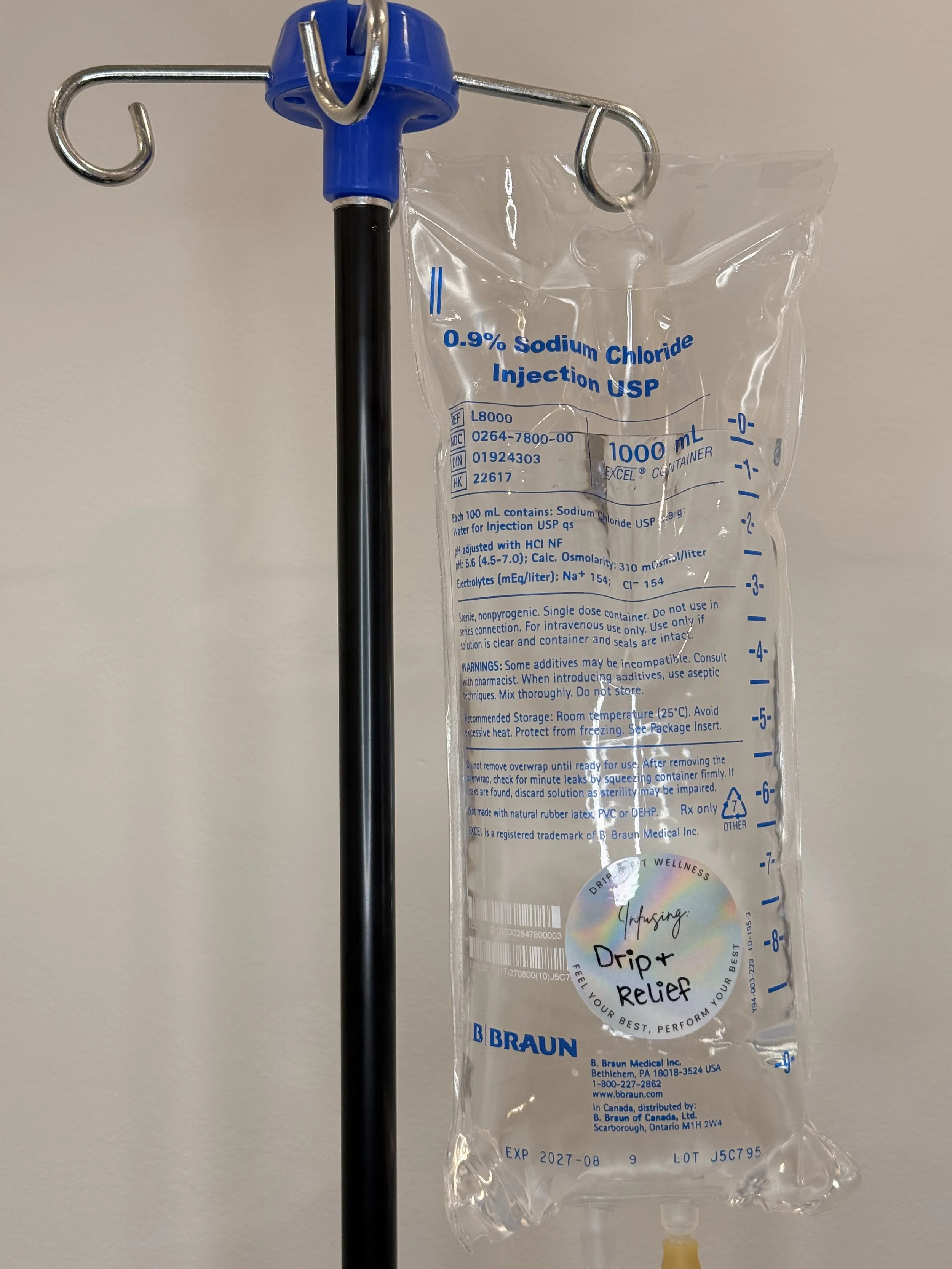 A medical IV bag labeled as 0.9% Sodium Chloride Injection USP hanging on a stand against a plain wall.