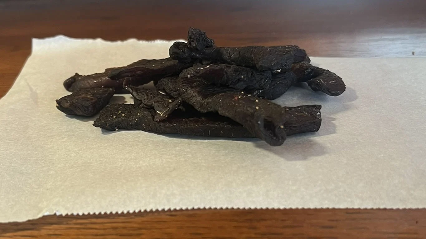 Pieces of dark beef jerky on parchment paper