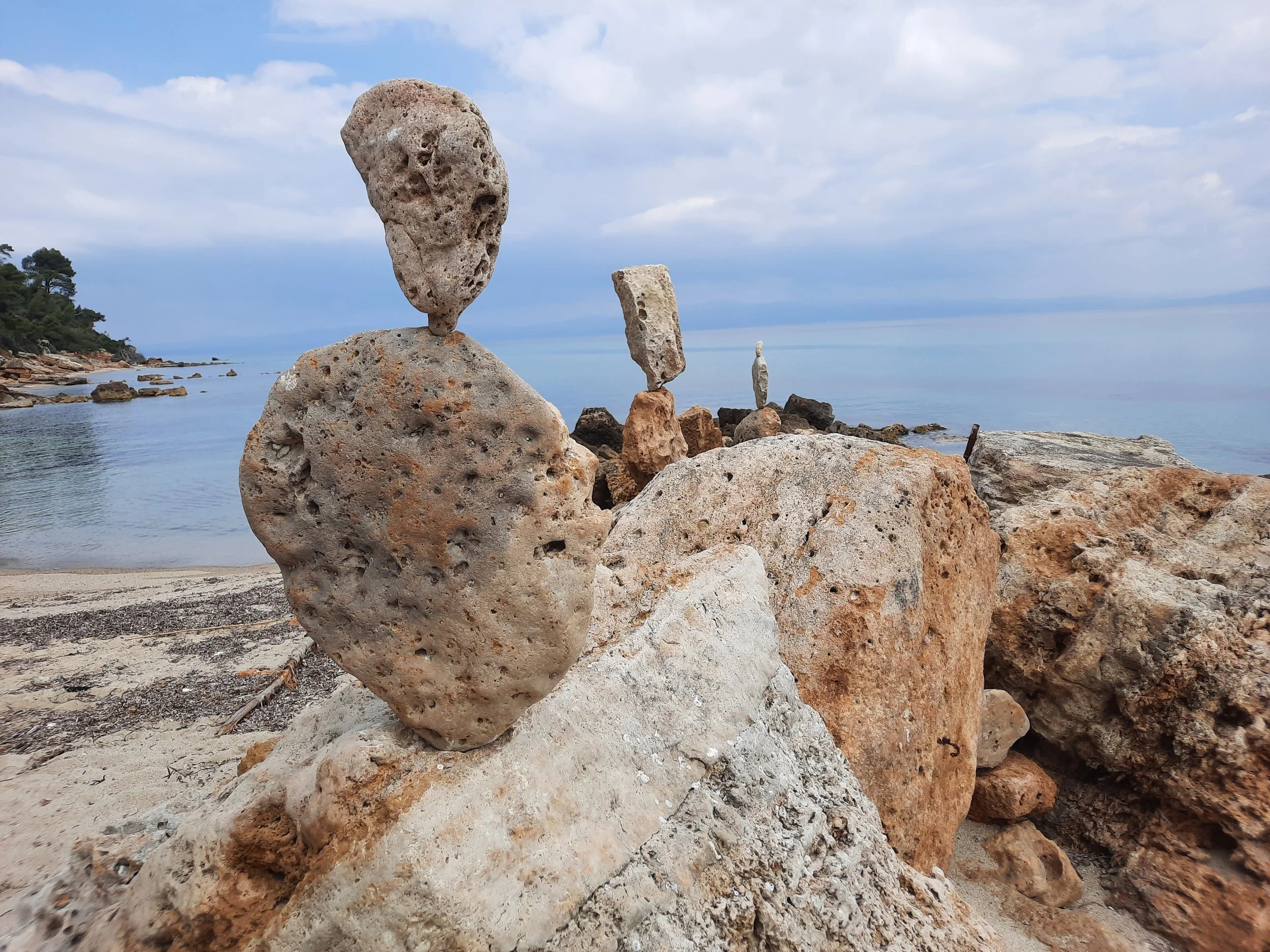 Steine und Felsen am Strand mit Blick auf das Meer und einen bewölkten Himmel.