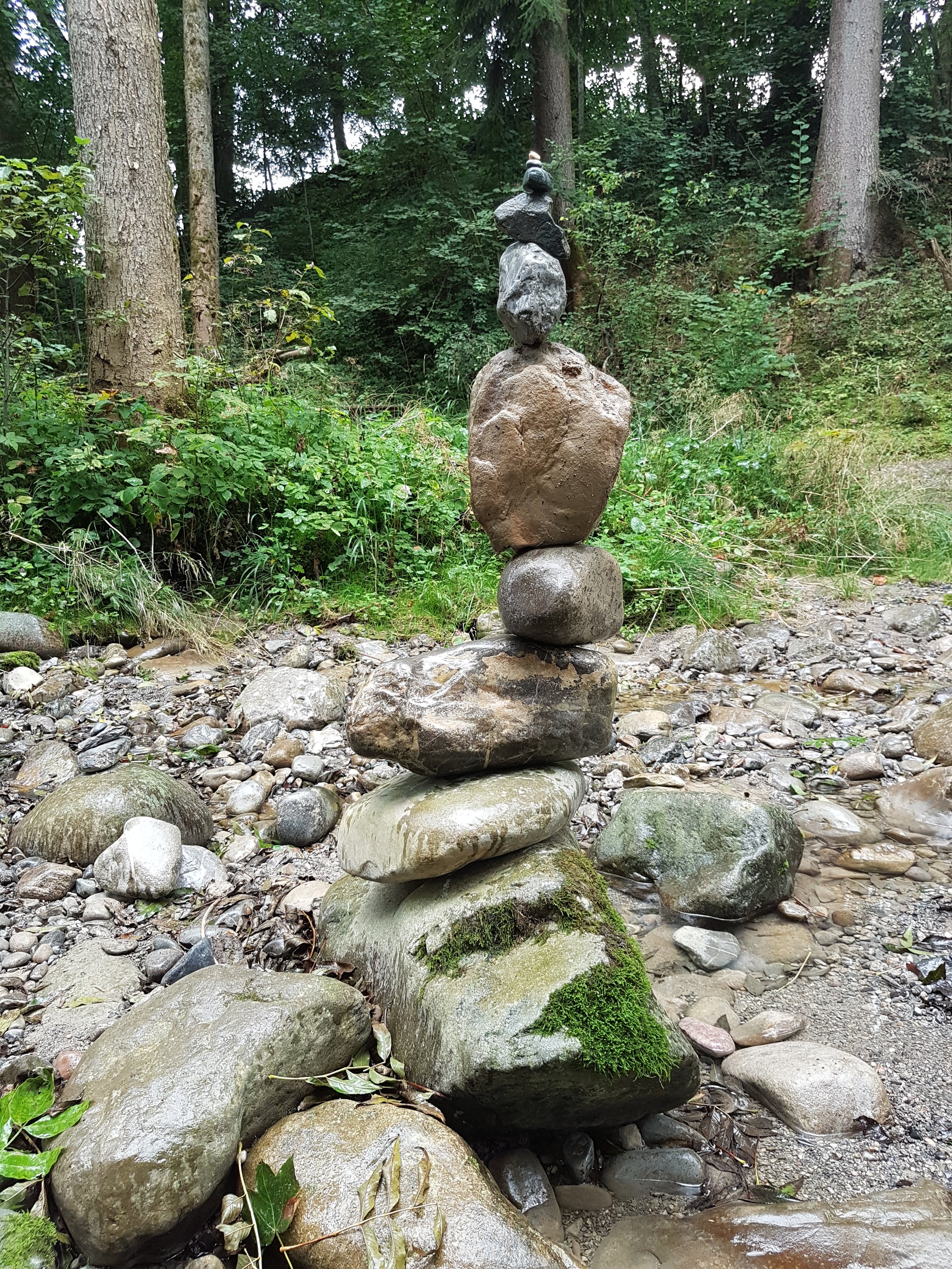 Ein Steinhaufen, der auf einem bewachsenen Felsen im Wald gestapelt ist.