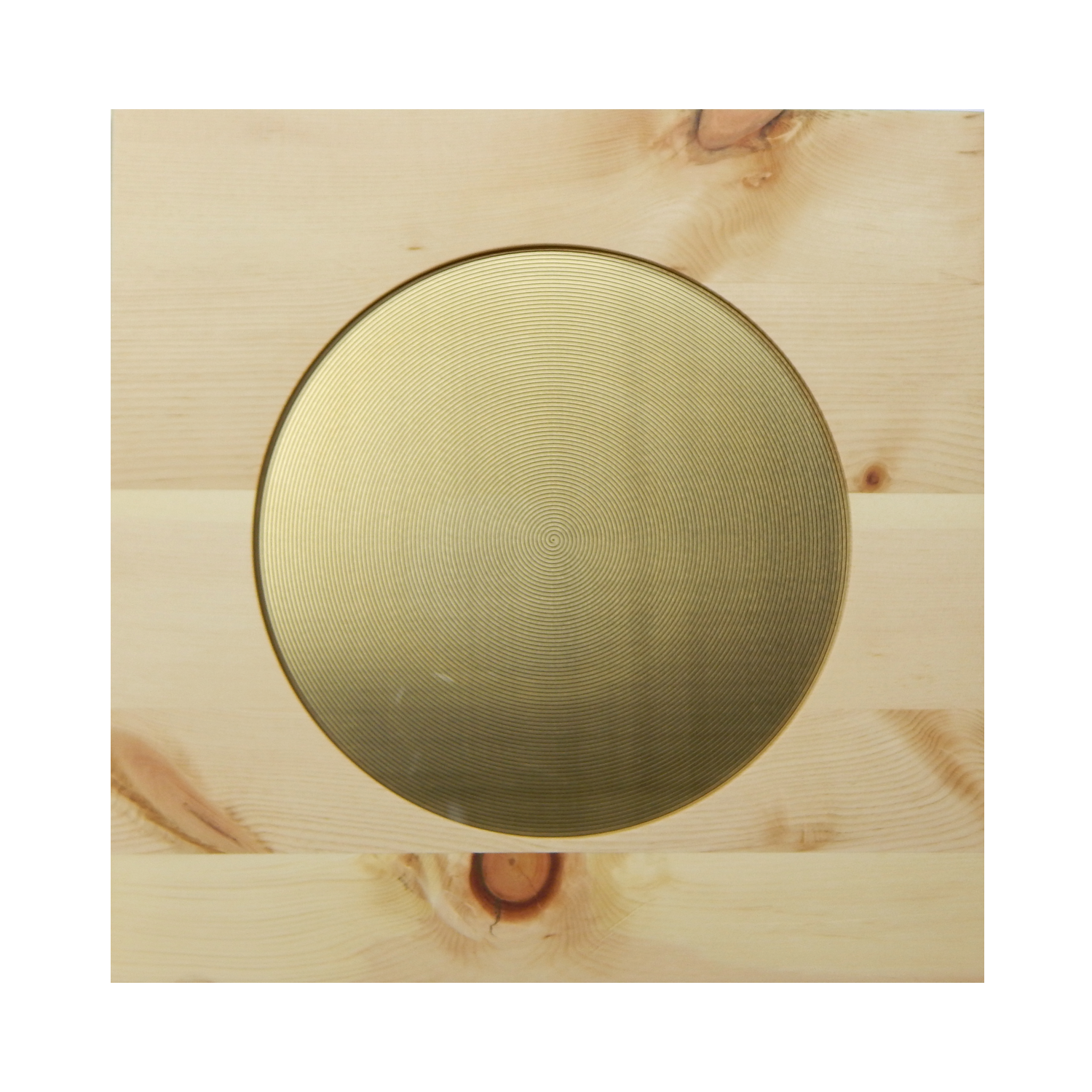 Ein runder, goldfarbener Gegenstand mit konzentrischen Kreisen auf einer Holzunterlage.
