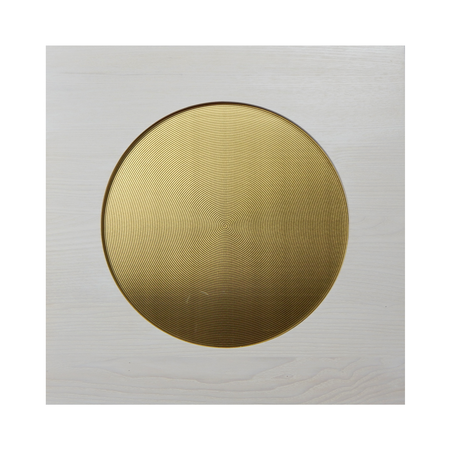 Ein runder, goldener, spiralförmiger Gegenstand auf einem weißen Holzoberflächenhintergrund.