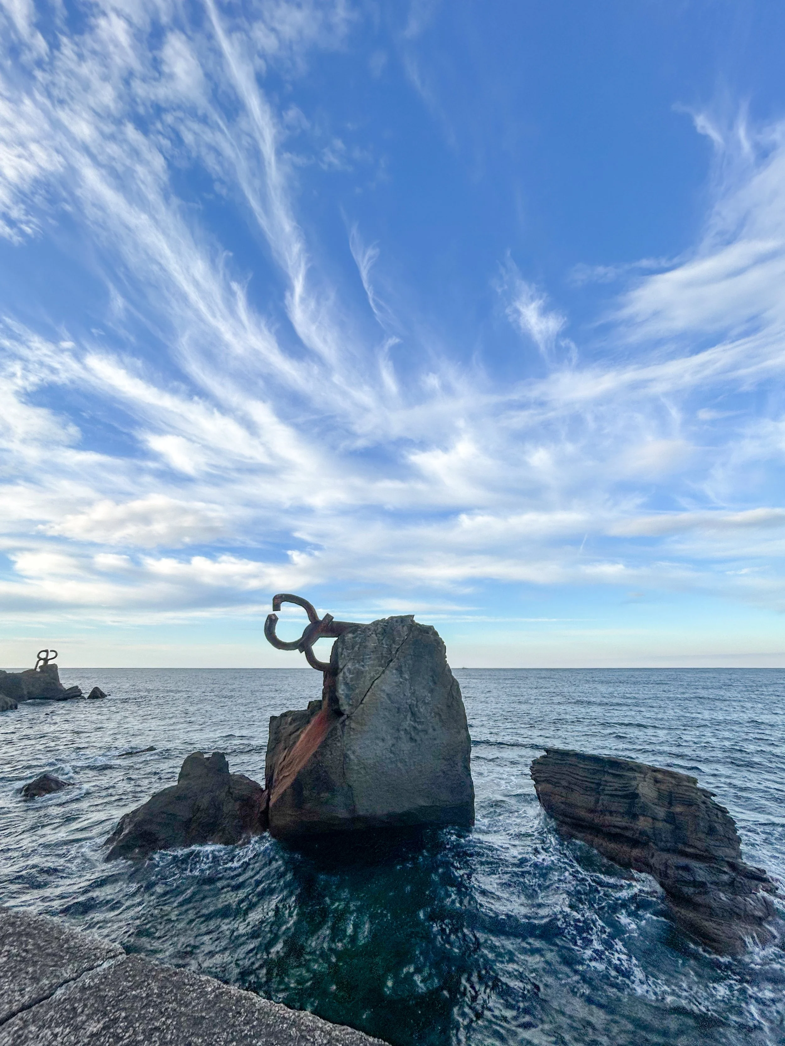 rocks with a metal sculpture off the shore in San Sebastián Spain