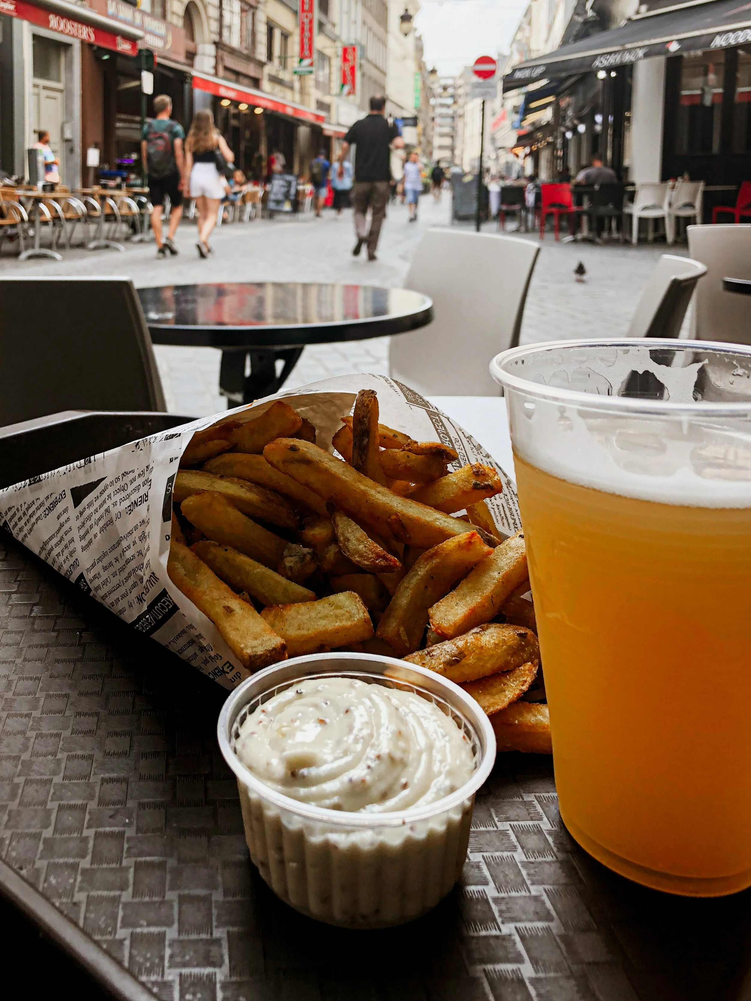 Belgian Fries and beer in a plastic mug on a storefront patio in Brussels