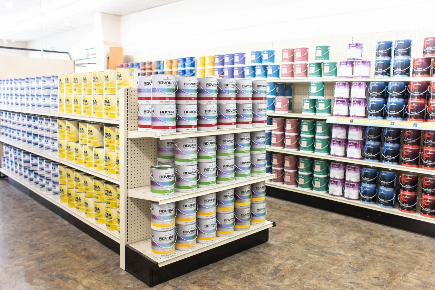 Shelves of colorful Benjamin Moore paint cans in a store.