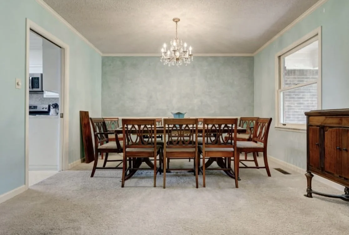 Elegant dining room with wooden table and chairs, chandelier, and teal walls.