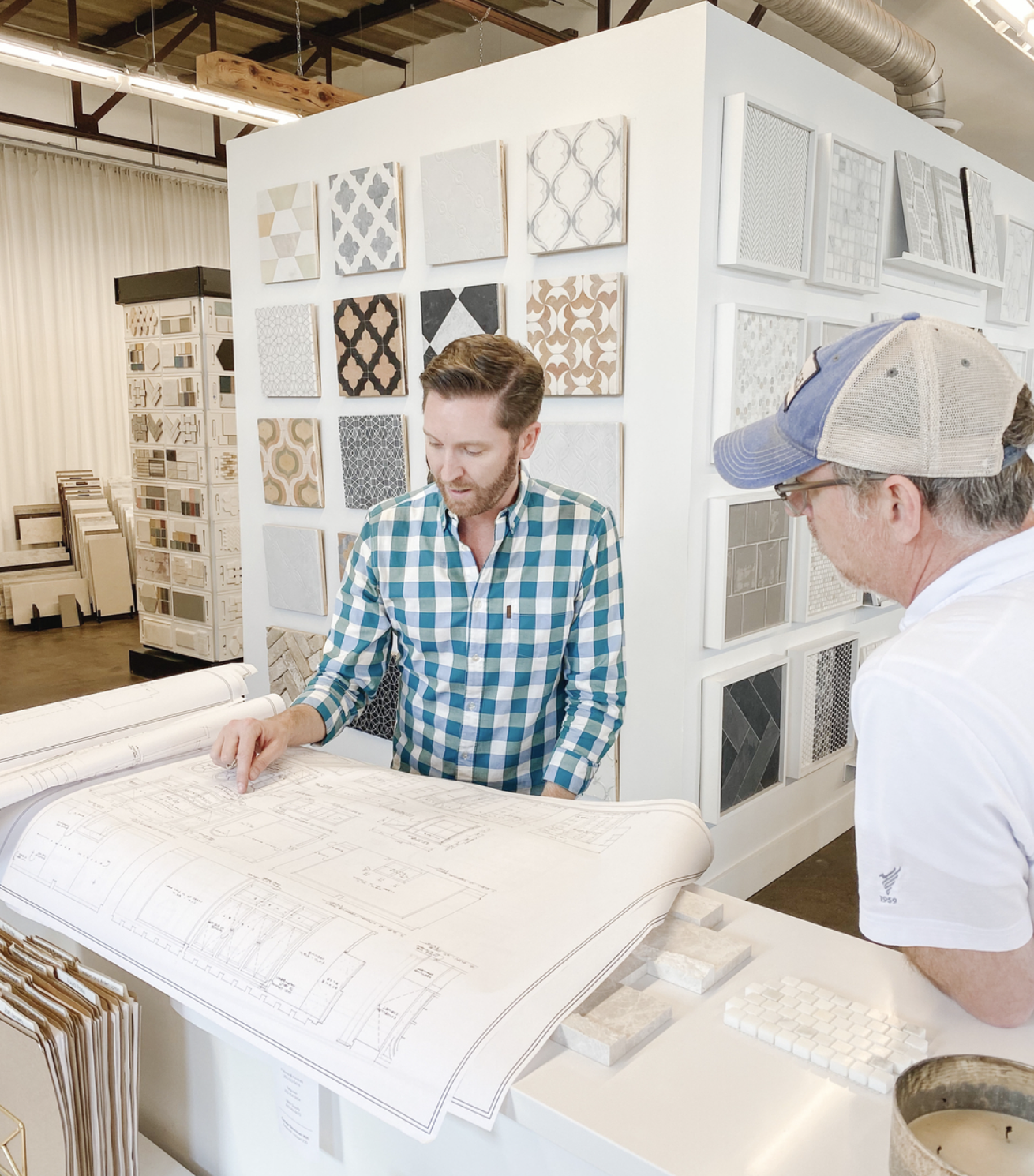 Two men examining architectural blueprints in a tile showroom.
