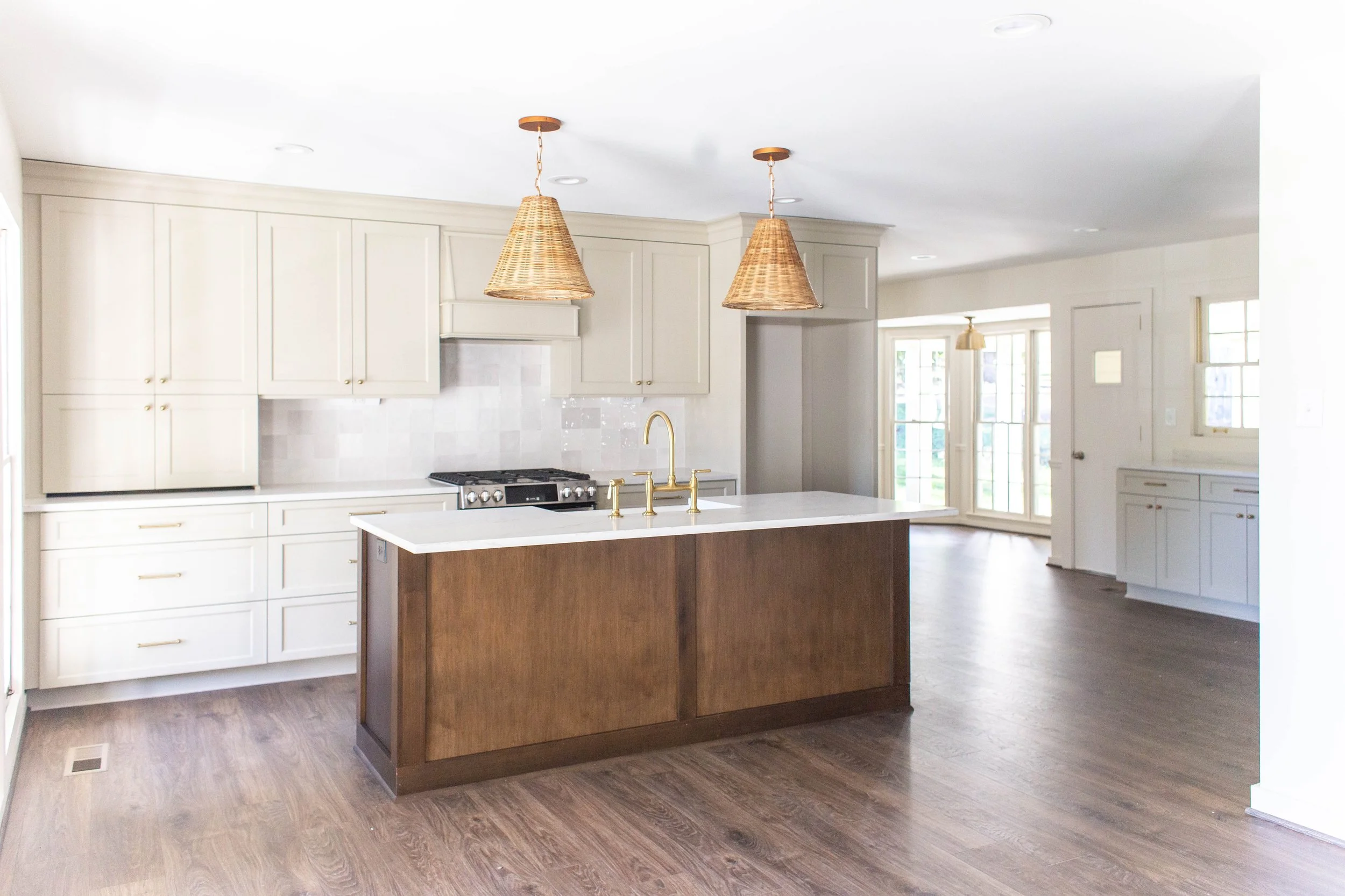 Modern kitchen with light cabinets, a wooden island, and wicker pendant lights.