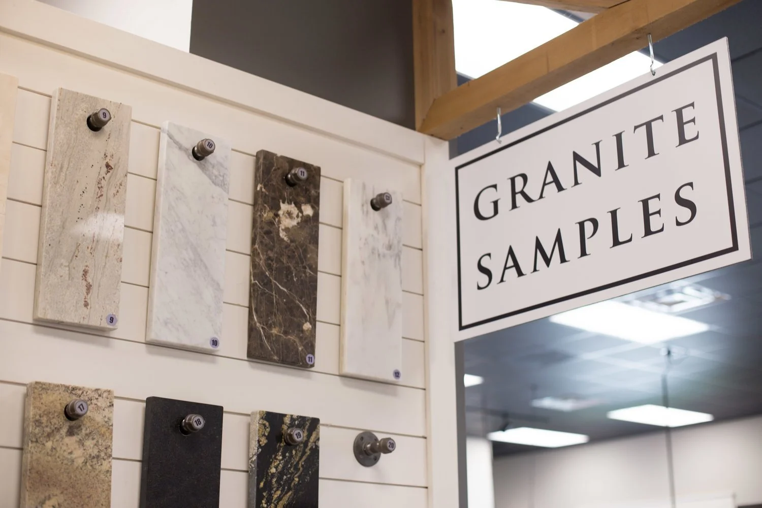 Various granite samples displayed on a wall in a store with a sign reading "Granite Samples."