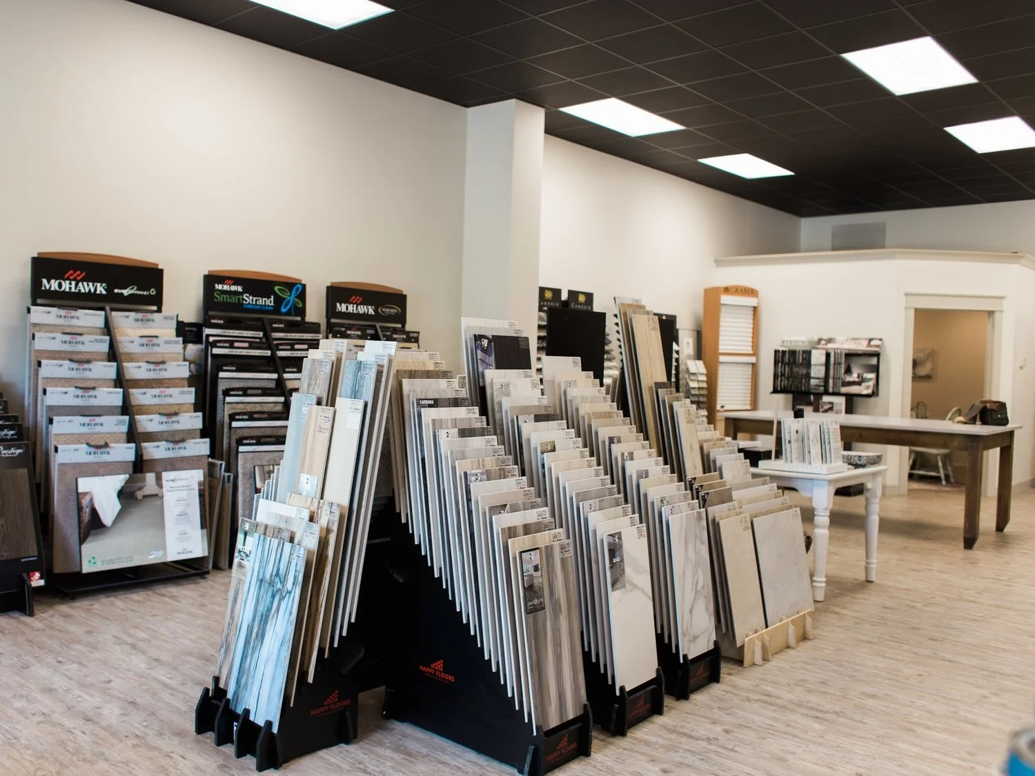 Interior of a flooring showroom featuring tile and carpet samples on display racks.