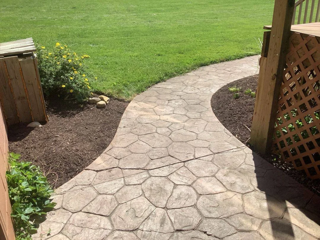 Curved stamped concrete path between freshly mulched planting beds — Genesee Valley Landscape