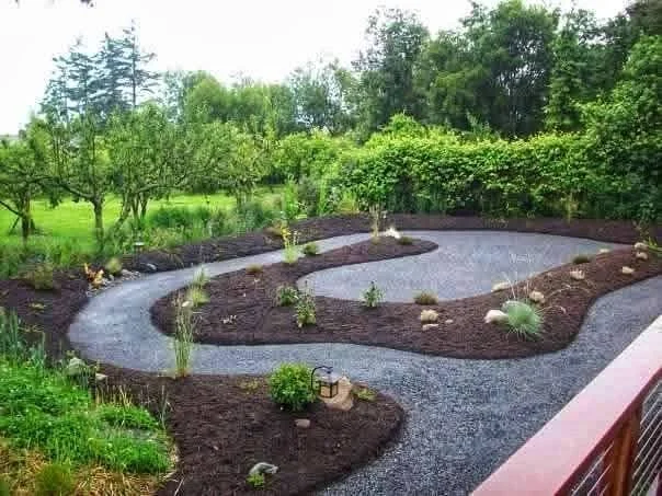 Curving gravel garden path winding through mulched planting beds — Genesee Valley Landscape