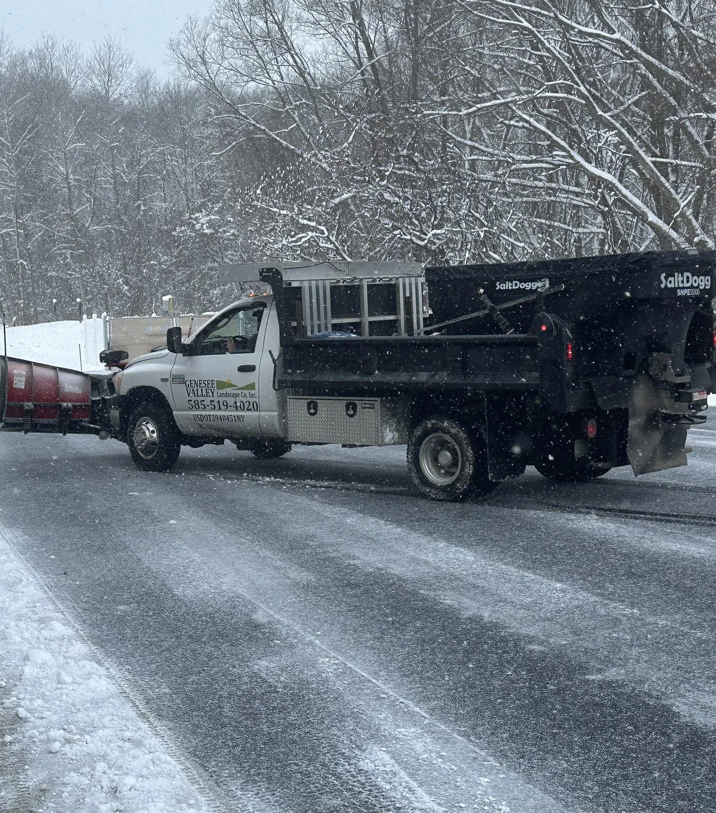 Genesee Valley plow truck with salt spreader clearing a commercial drive lane during snowfall in Livingston County, NY