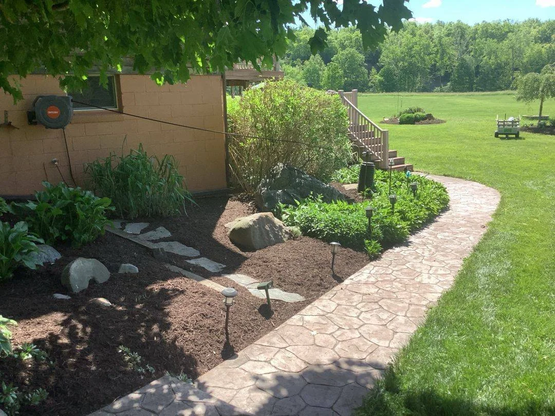 Stamped concrete walkway with low-voltage path lights and stepping stones — Genesee Valley Landscape