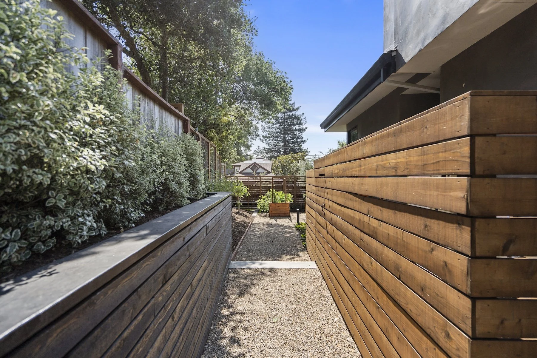 Pebble walkway and wooden retaining wall by Heritage Landscapes