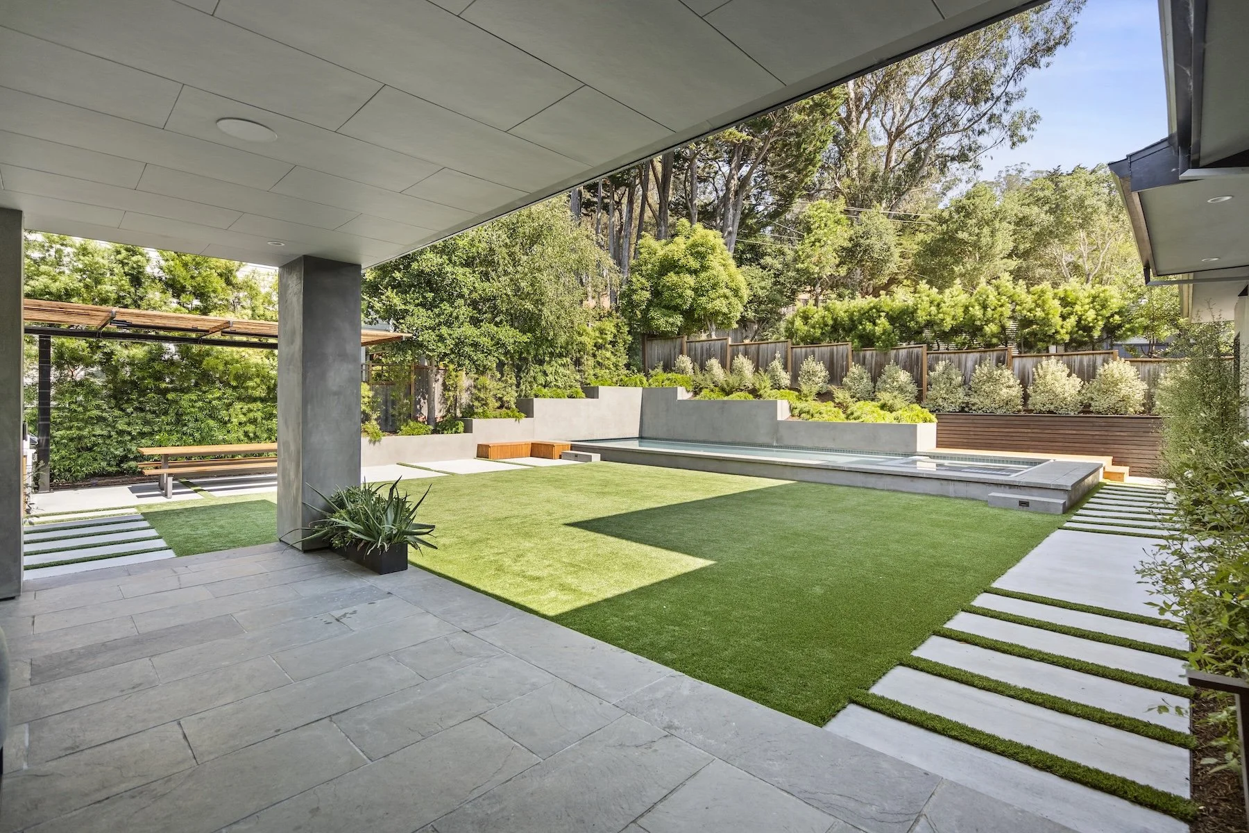 Artificial turf in modern backyard with concrete walkway