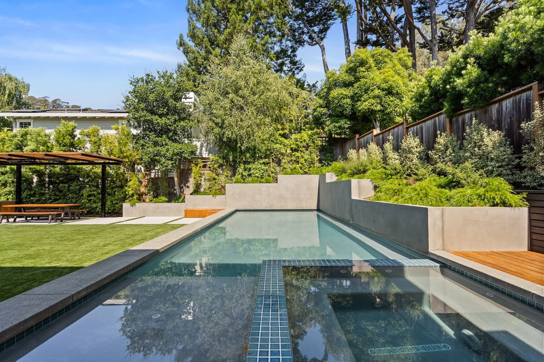 Inground pool with wooden pergola and outdoor kitchen