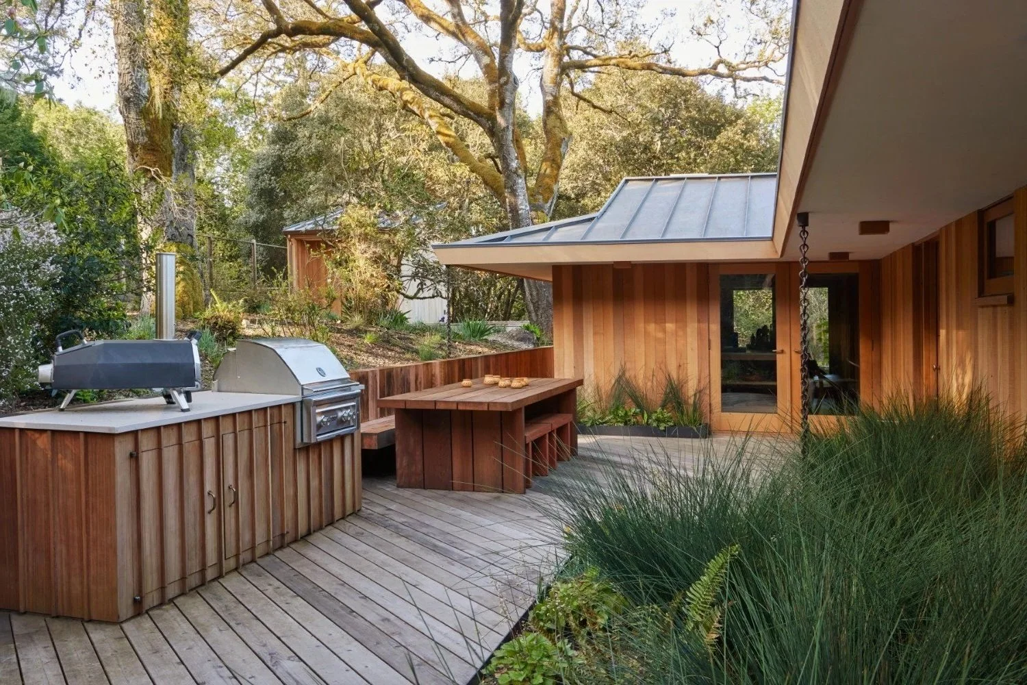 Outdoor kitchen, wooden patio, and seating area in a residential backyard