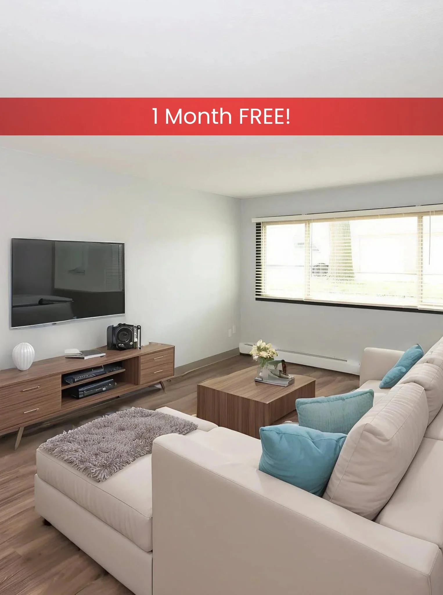 Modern living room in apartments in Rochester with cream sofas, light wood furniture, wall art, large TV, and natural light.
