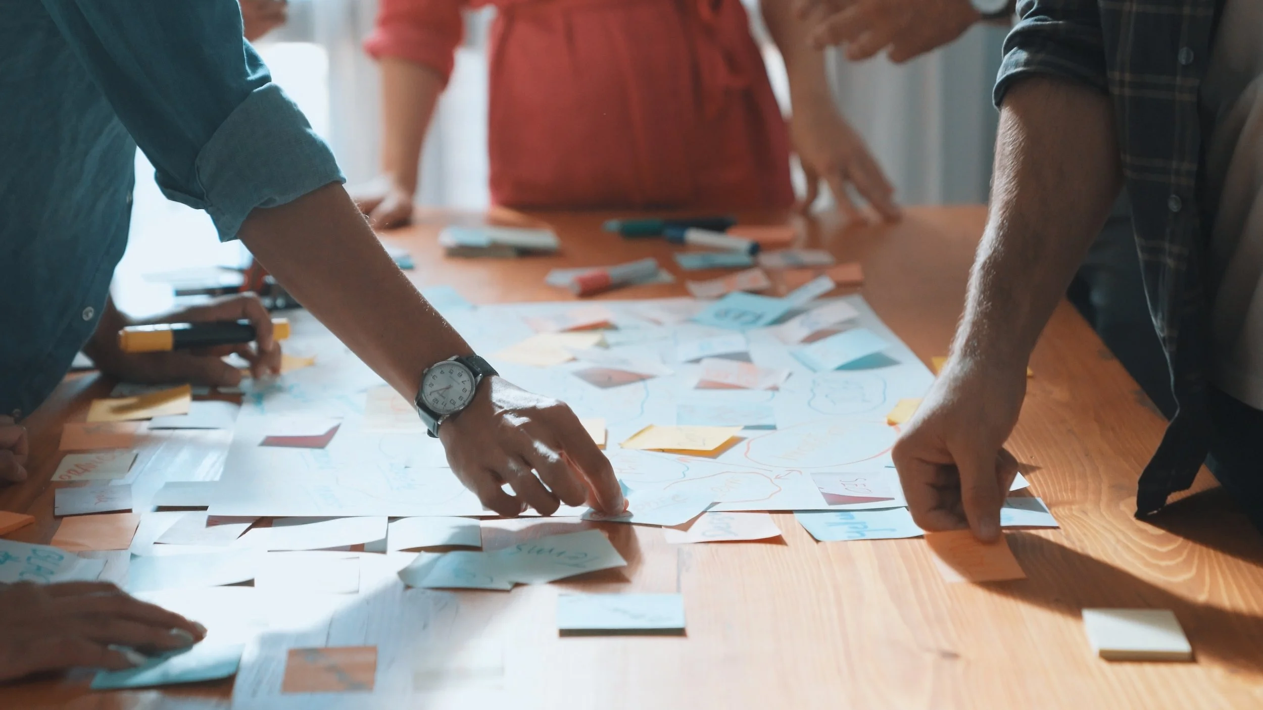 People gathered around a table, working on a project with colorful sticky notes and markers.