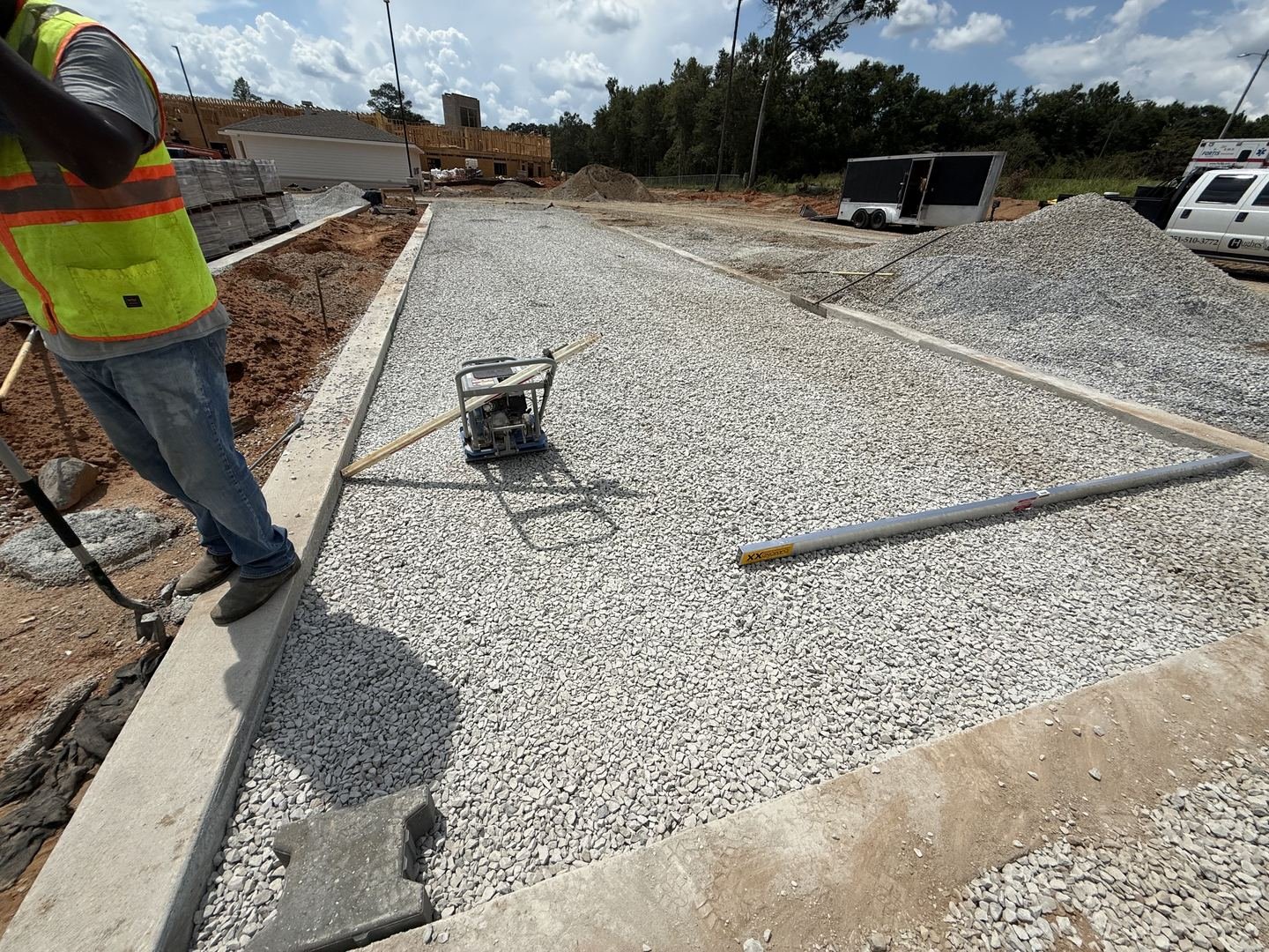 Site Work: Permeable Paver Lot & Retaining Wall — stone base and curbs being set for the paver lot, Hughes 360 Services