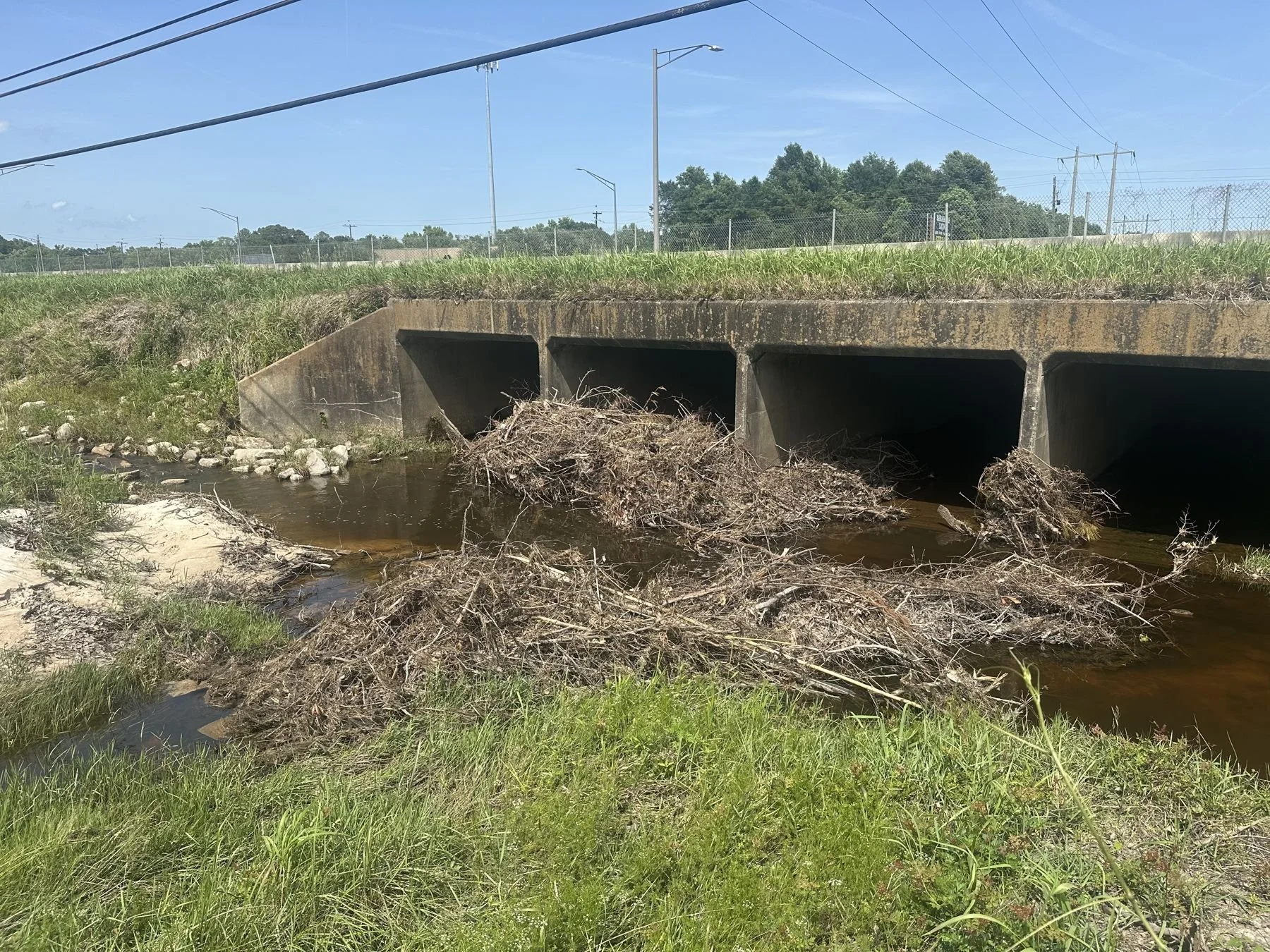 City of Mobile storm drainage ditch clearing — debris-clogged box culvert before cleaning
