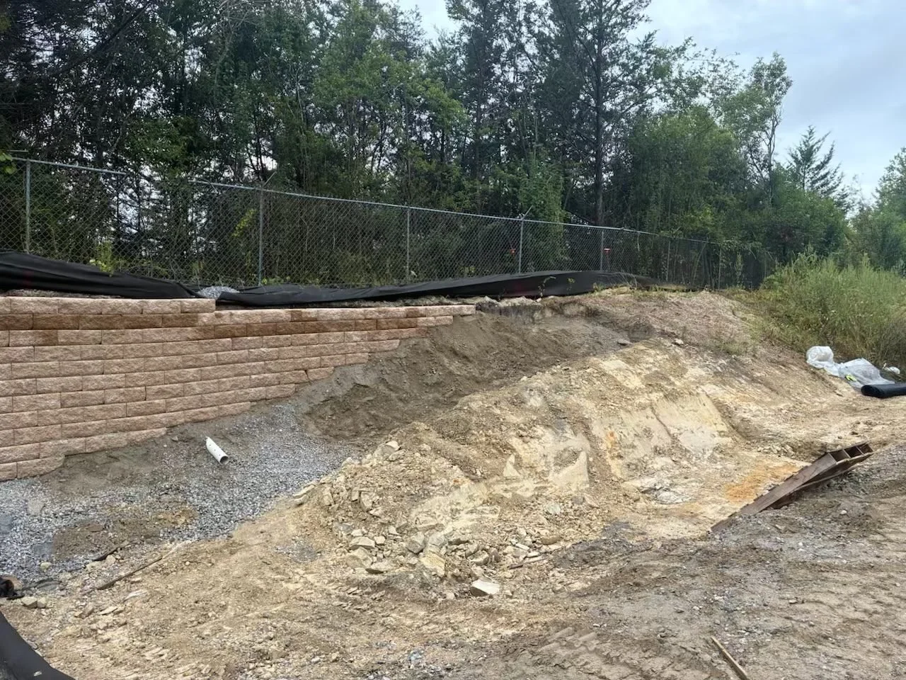 Site Work: Permeable Paver Lot & Retaining Wall — retaining wall nearing completion, Hughes 360 Services