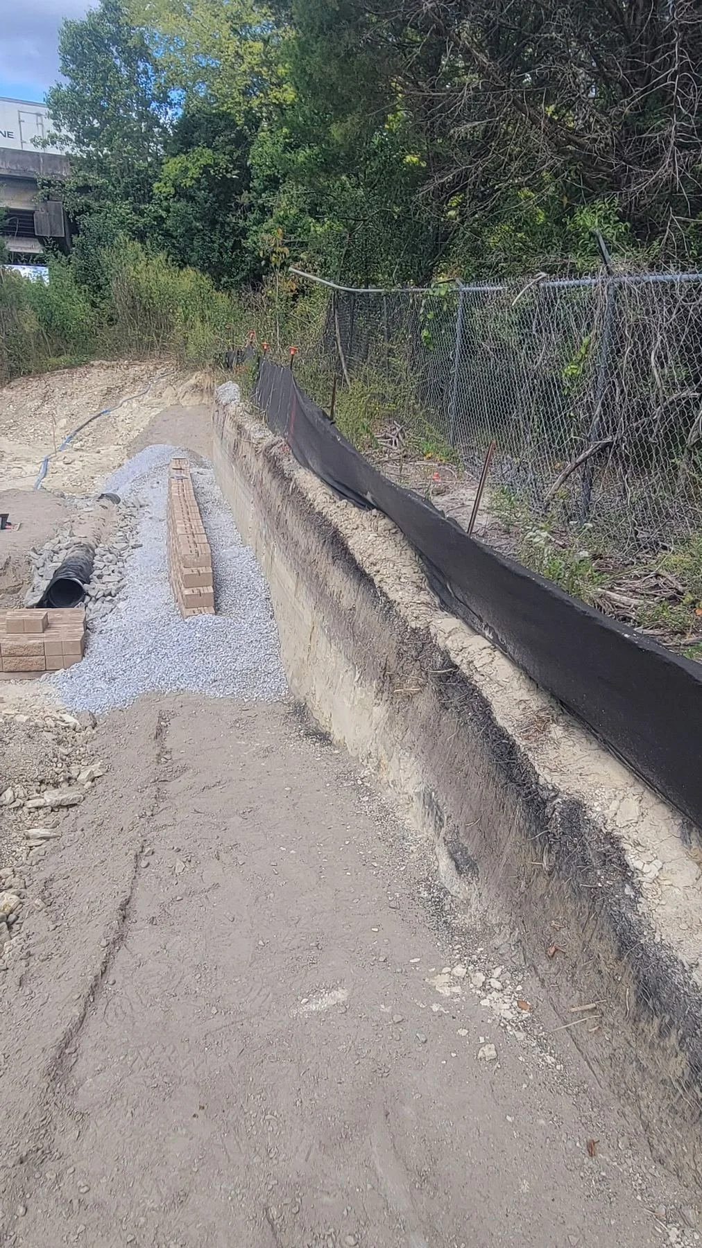 Site Work: Permeable Paver Lot & Retaining Wall — drainage pipe set behind the wall, Hughes 360 Services