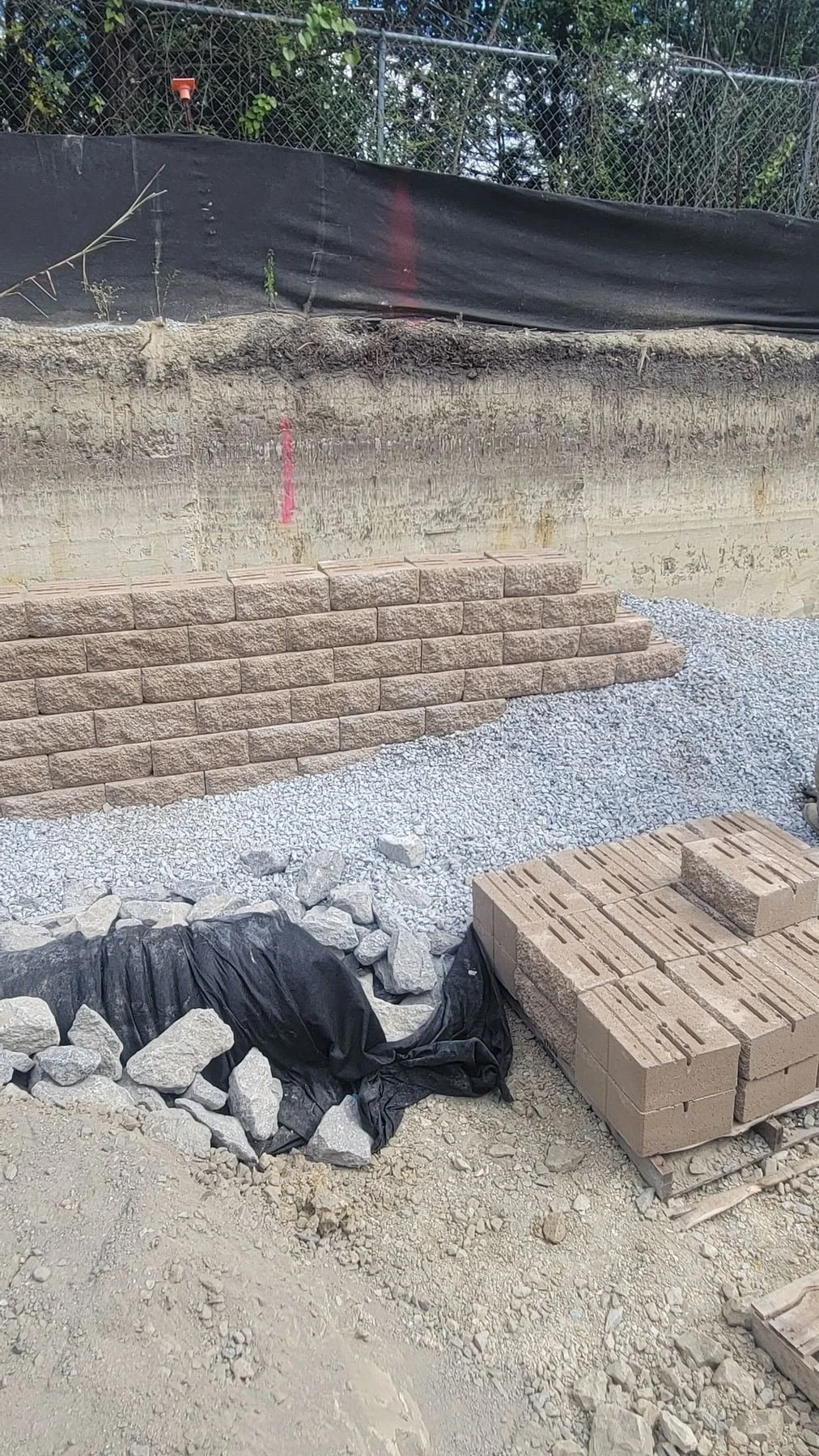 Site Work: Permeable Paver Lot & Retaining Wall — segmental block wall taking shape, Hughes 360 Services