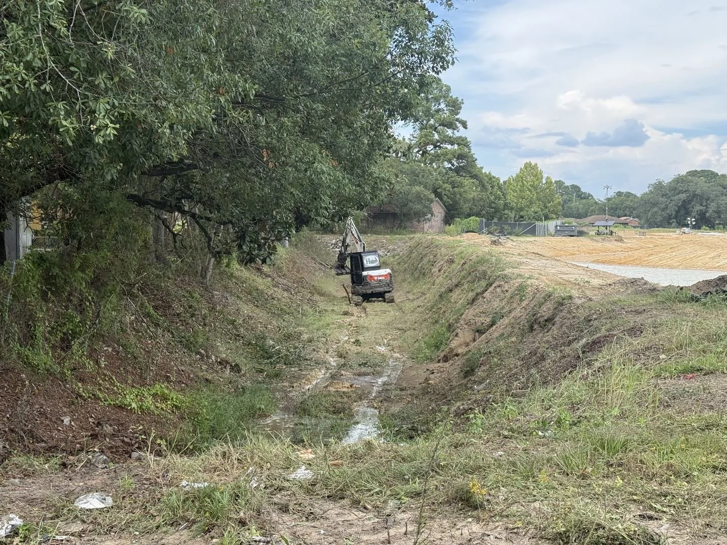 City of Mobile storm drainage ditch clearing — excavator cutting the creek bank, Hughes 360 Services