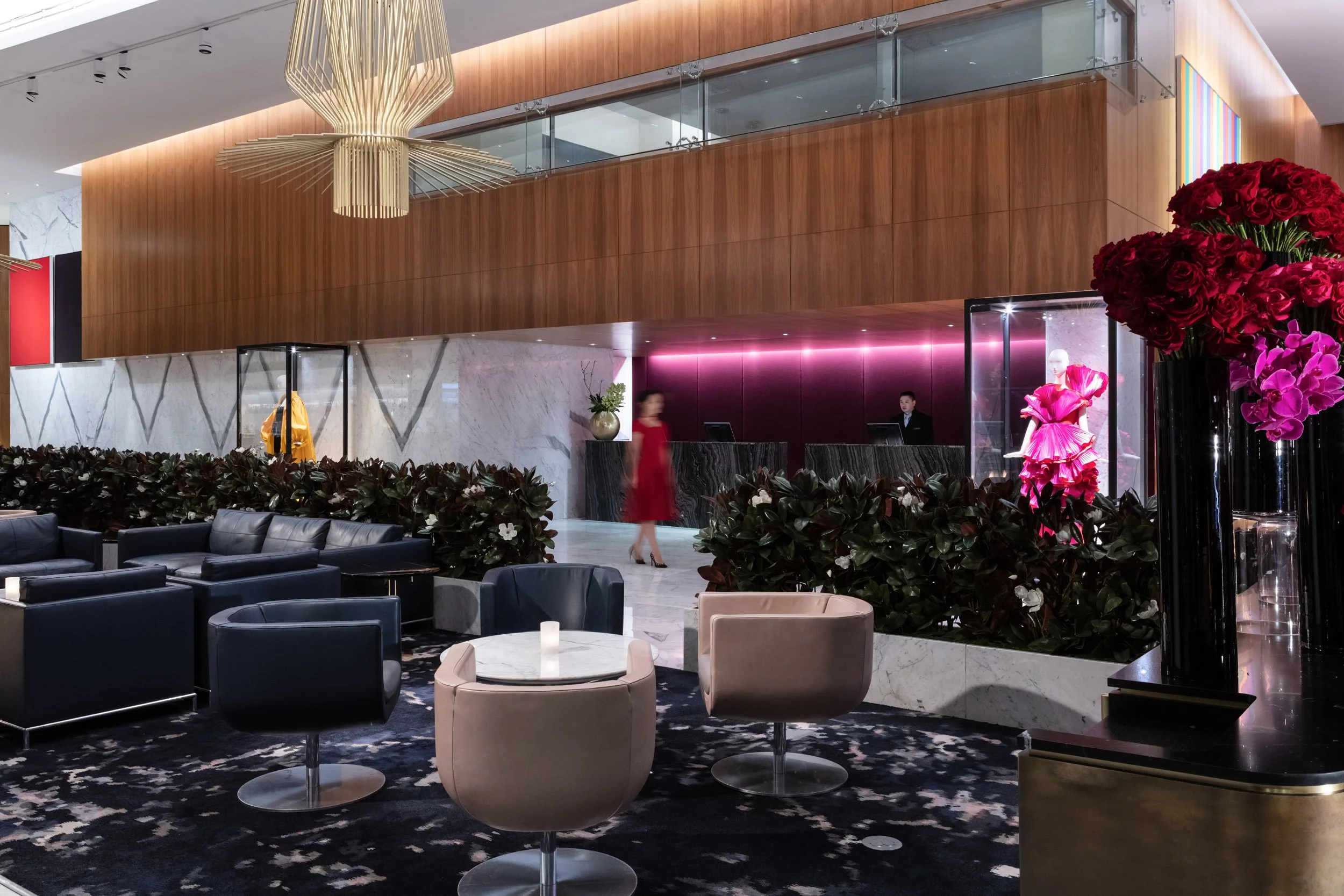 Hotel lobby with seating area, reception desk, and floral arrangements.