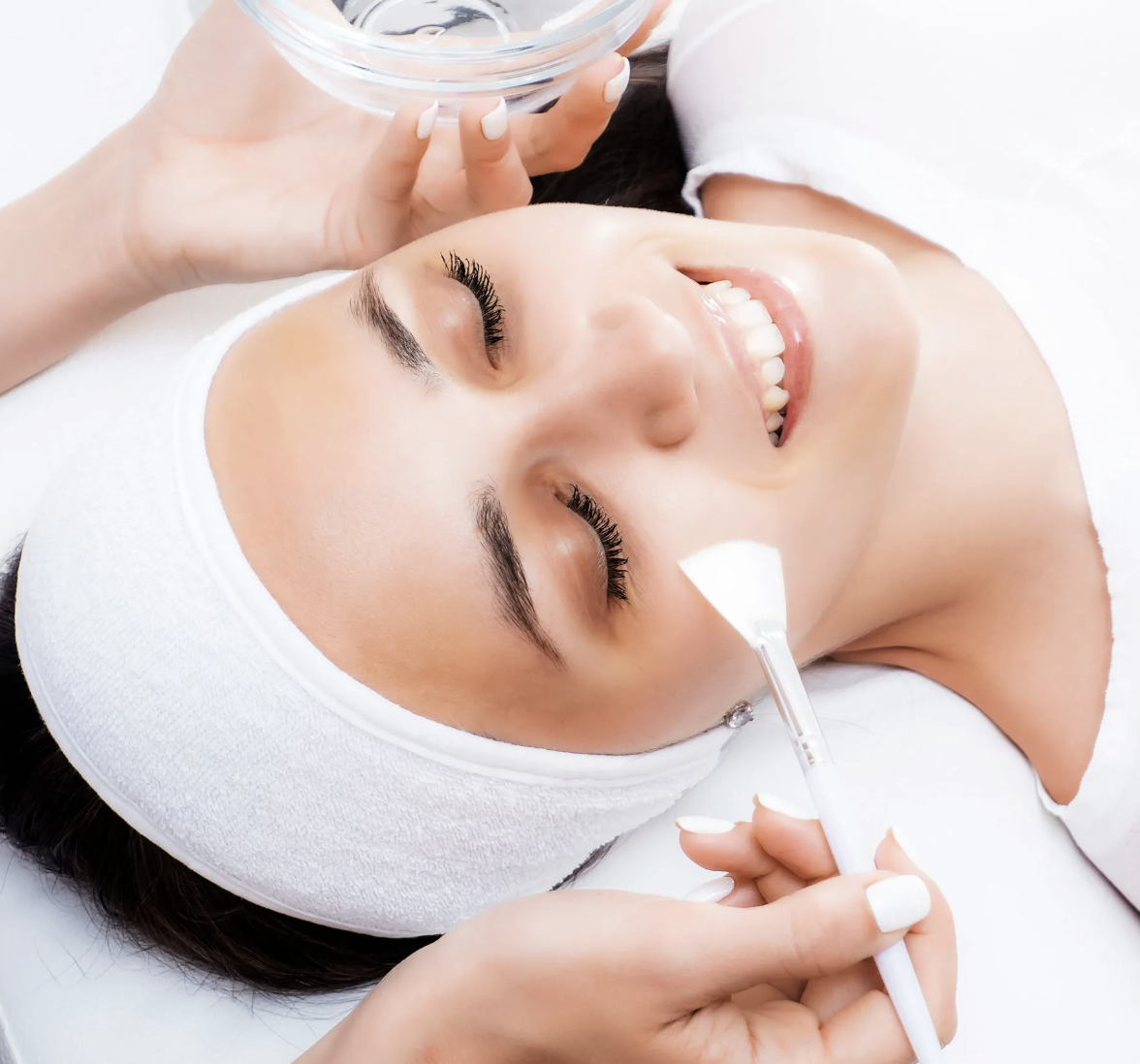 Woman receiving facial treatment with a brush and bowl