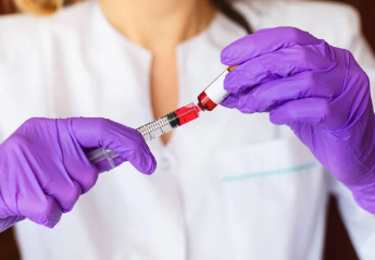 Person wearing purple gloves filling a syringe with red liquid