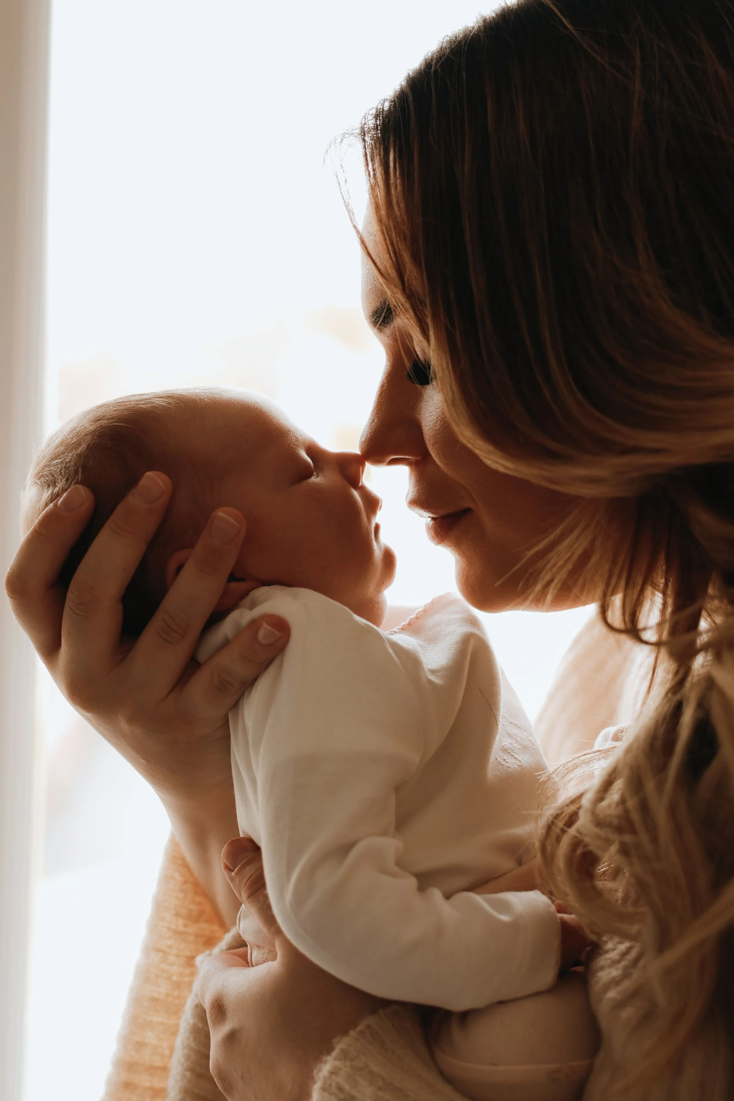 A woman holding a baby close, touching noses in a tender moment. Newborn photography, Portsmouth 