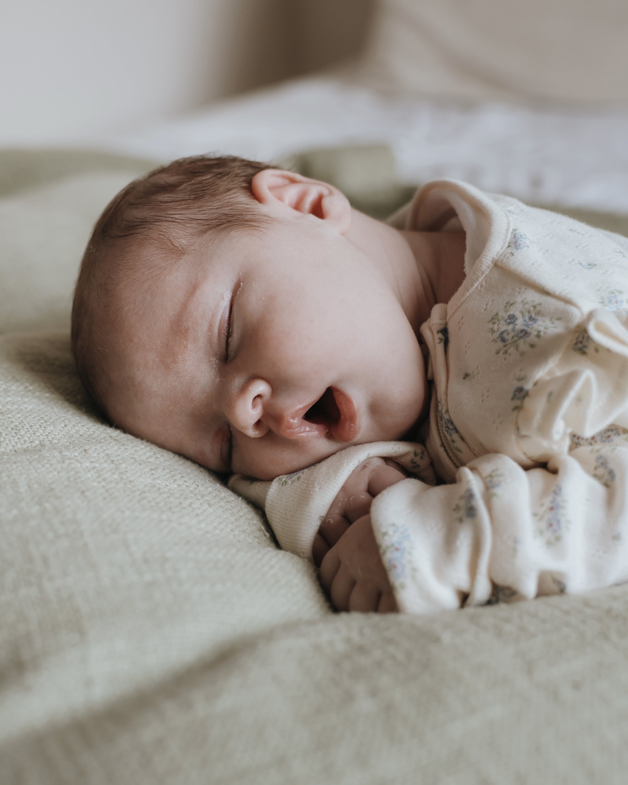 Close-up view of a sleeping baby with a peaceful expression, lying on a soft surface.