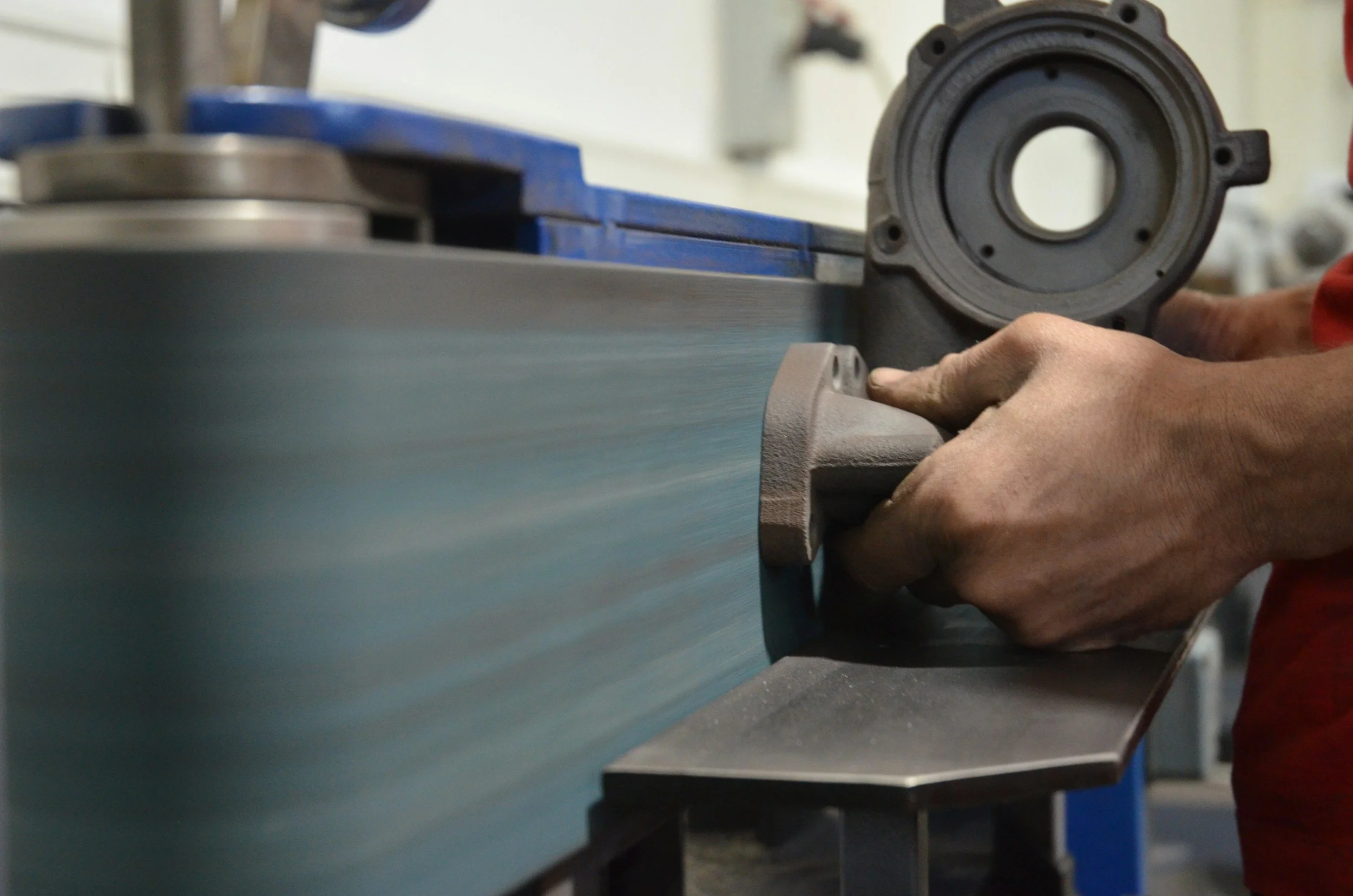Close-up of a person's hand operating a grinding or polishing machine in an industrial or workshop setting.