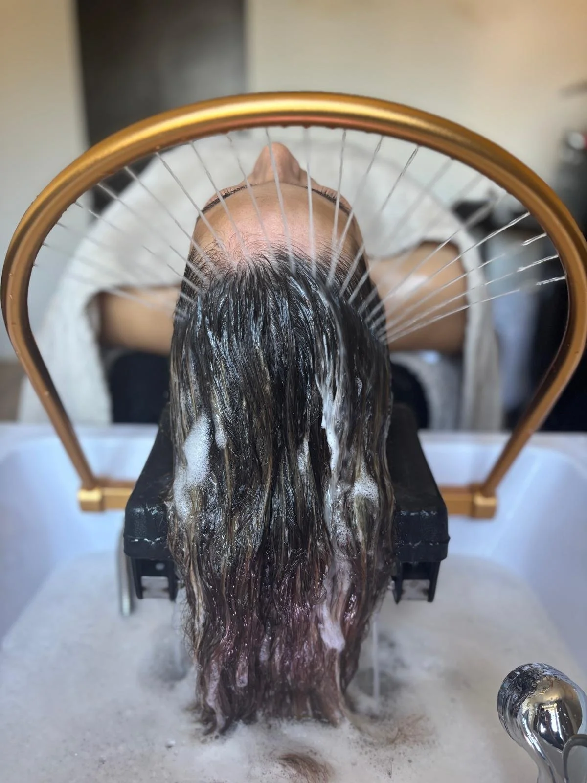 Persoon die harslapje krijgt met lokons haar onder water, met een ronde spiegel en zeepbellen.