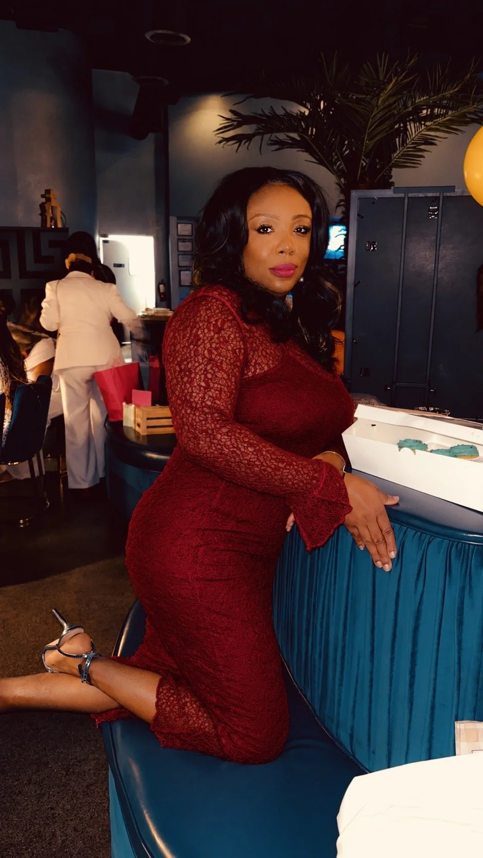 Woman in red dress smiling at a table with dim lighting