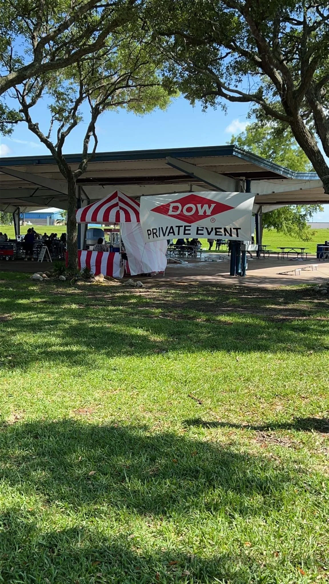 Outdoor pavilion with a sign reading "DOW PRIVATE EVENT" and a striped red and white tent for a private gathering.