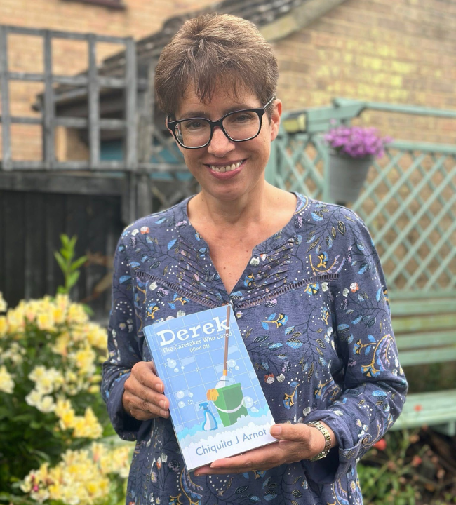 A photo of chiquita j arnot holding her book Derek: The Caretaker Who Cared (Kind Of)