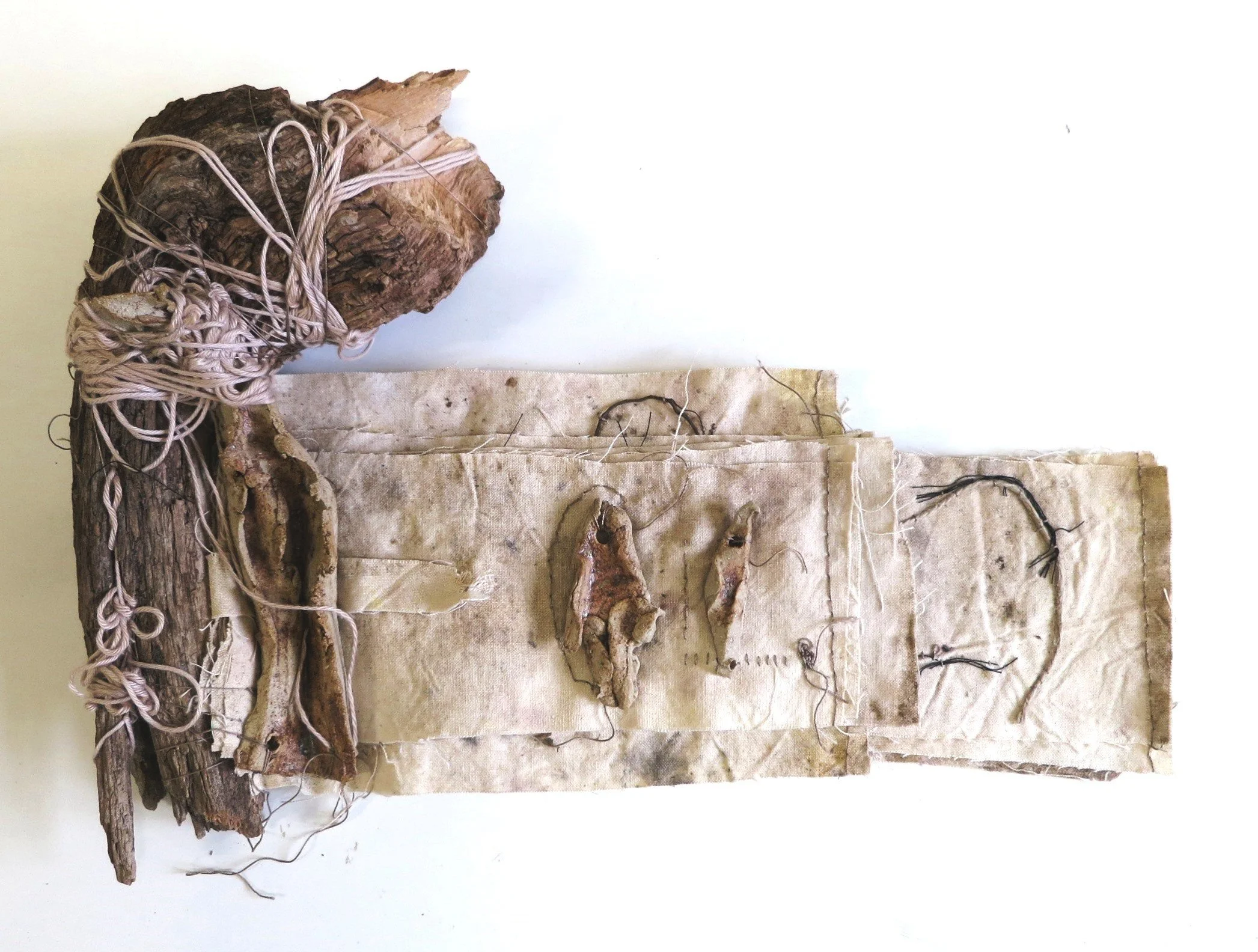 Une œuvre d'art composée de bois, cordages et matériaux de récupération assemblés sur une planche en bois, évoquant une composition abstraite ou une sculpture artisanale.