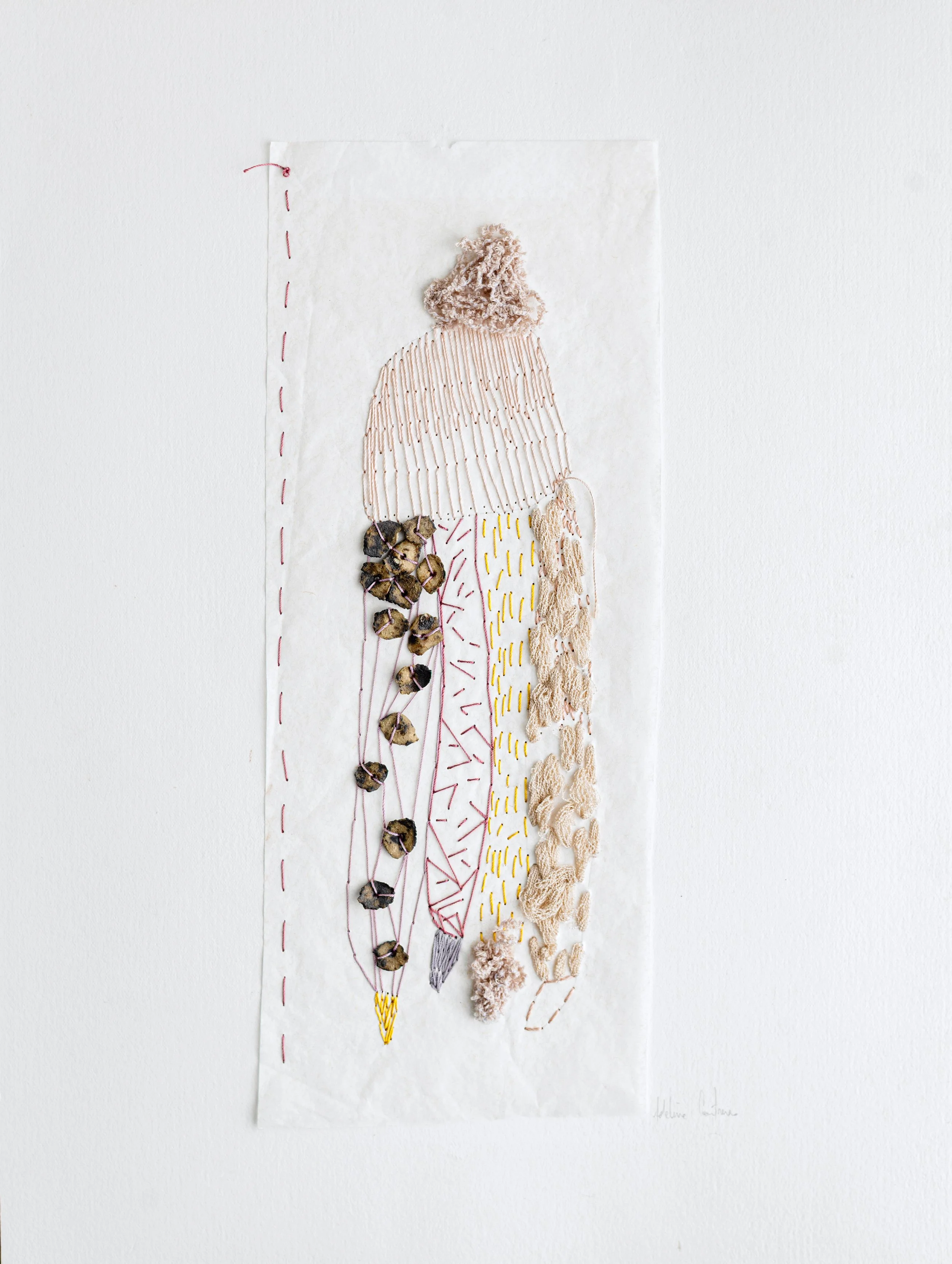 Une œuvre d'art utilisant des matériaux textiles et des éléments naturels pour représenter une figure humaine stylisée avec une robe et une tête de laine beige, accompagnée de détails brodés et de graines séchées.