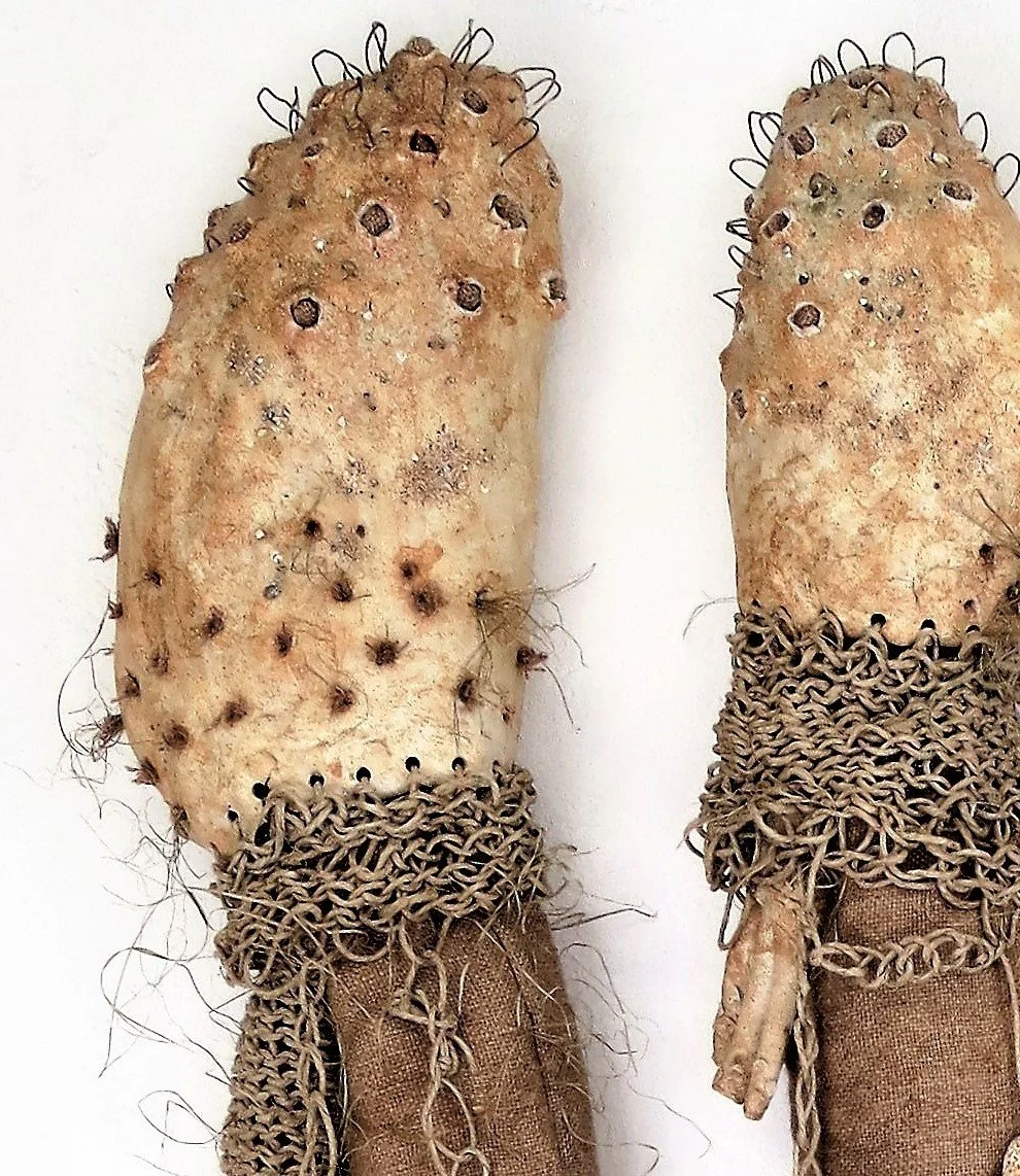 Deux légumes ressemblant à des patates, enfilés dans des chaussettes en tissu avec des chaînes en métal autour du haut, créant une apparence de visages anthropomorphes.