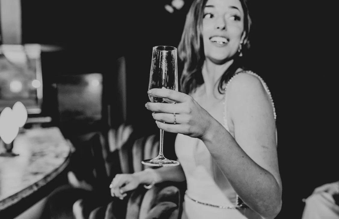 A woman in a dress holding a glass of wine at a social gathering or celebration.
